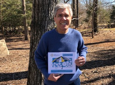 Fabry disease terminology | Fabry Disease News | photo of Jerry standing in the woods among tall pine trees and holding a document