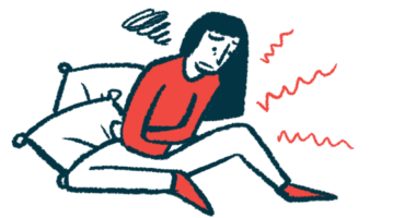 A woman sitting on the floor is clutching her stomach in pain.