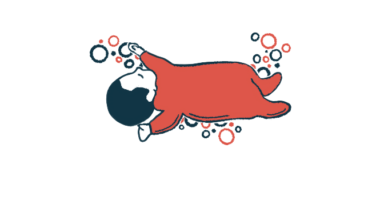 An infant in a red onesie naps with arms and legs outstretched.